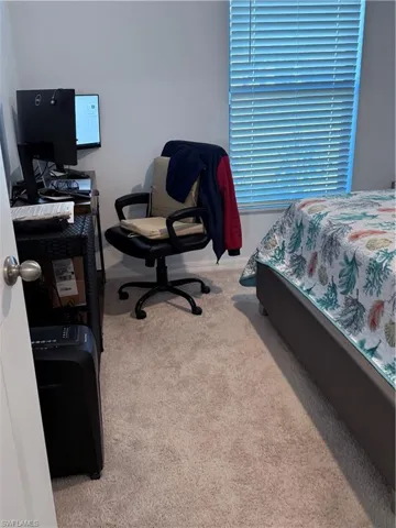 Bedroom with light colored carpet and an office area