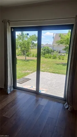 Sliding glass door opening to a paver patio and a grassy area