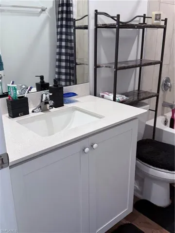 Bathroom with vanity, dark wood finished floors, and shower / bath combo with shower curtain