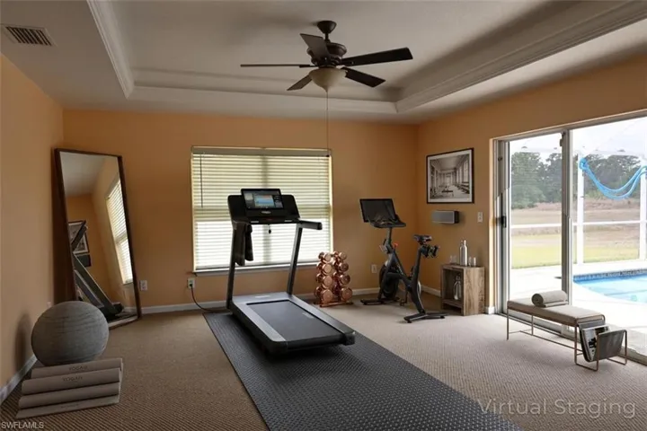 Exercise room with a raised ceiling and ceiling fan
