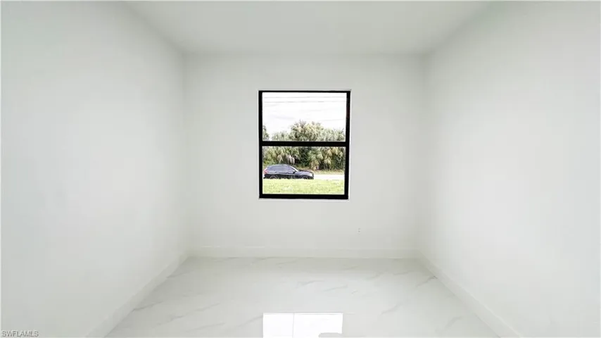 Neutral white wall finishes, single window with black framing, and large-format tile flooring