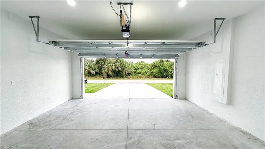 Concrete flooring, automatic garage door opener, recessed lighting, and a paved driveway