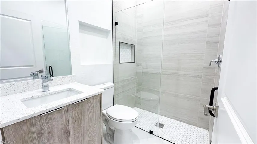 Vanity with a white speckled countertop, integrated sink, and wood-finish cabinetry