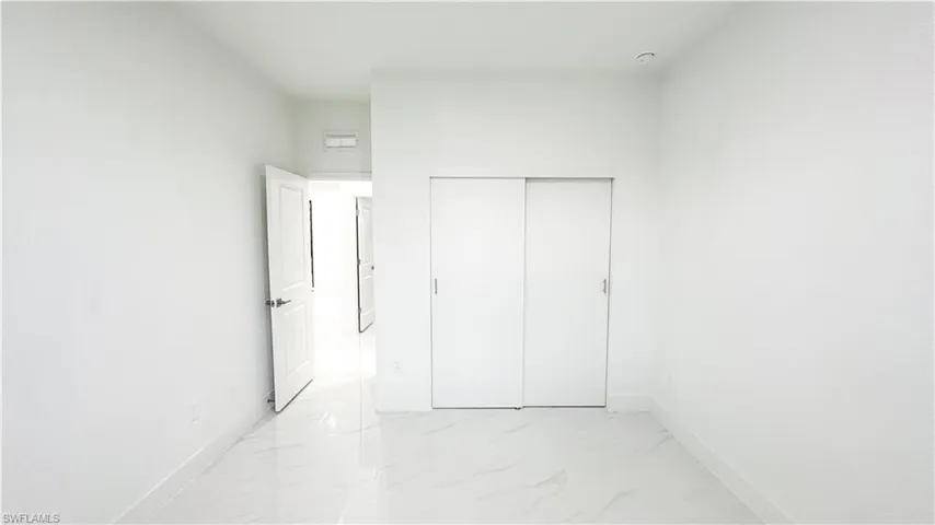White walls, white tile flooring, white baseboards, white solid doors, white sliding closet doors