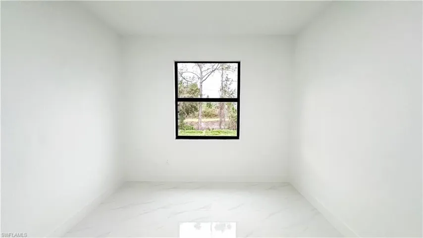 White walls, white tile flooring, and a black-framed window