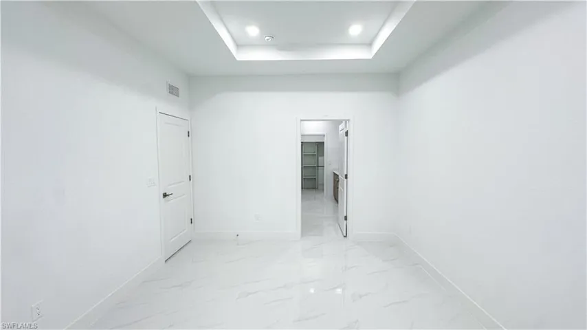 Recessed ceiling with integrated lighting, white walls, and large format tile flooring