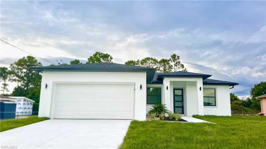 White stucco exterior with a dark shingle roof, integrated two-car garage, covered entry, and decorative landscaping