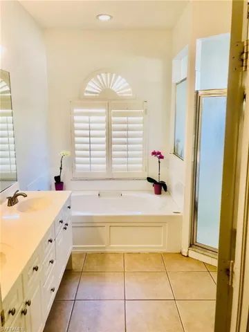 Master Bathroom with separate shower and tub, vanity, and tile floors