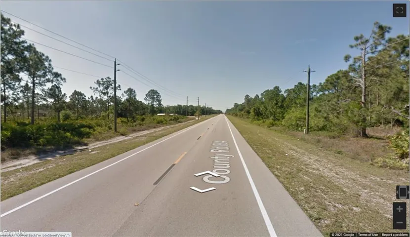 View of asphalt road featuring view of wooded area