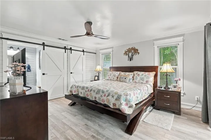 Wood-finish flooring, ceiling fan, and white barn doors