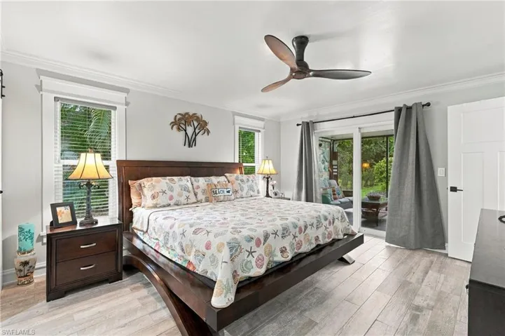 Light wood-finish flooring with crown molding and a modern ceiling fan