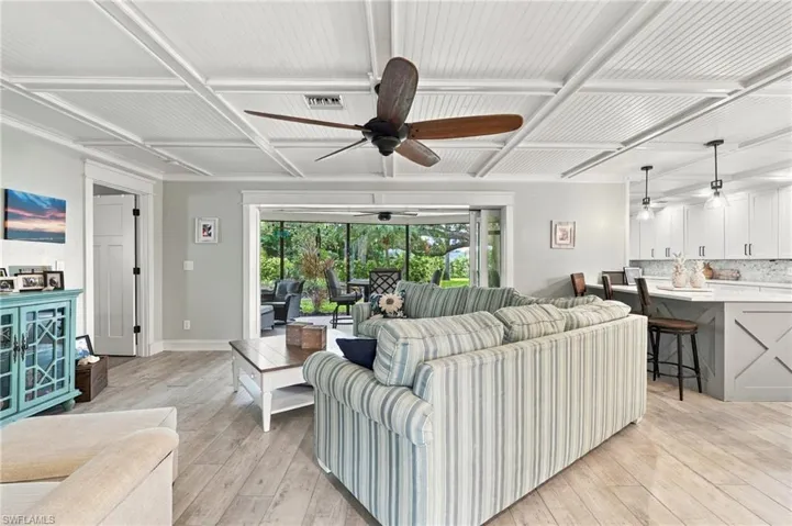 Coffered ceiling with beadboard panels, wood-finish flooring, recessed lighting, white shaker cabinetry, and a kitchen island with seating
