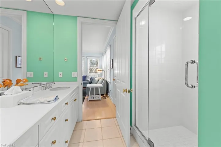 Ensuite bathroom with vanity, a shower stall, and tile patterned flooring