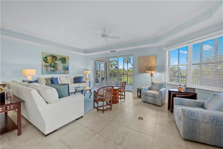 Living area featuring a tray ceiling, ornamental molding, ceiling fan, and light tile patterned floors