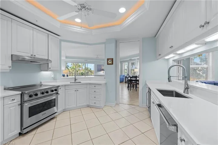 Kitchen featuring stainless steel appliances, under cabinet range hood, a sink, a ceiling fan, and light countertops