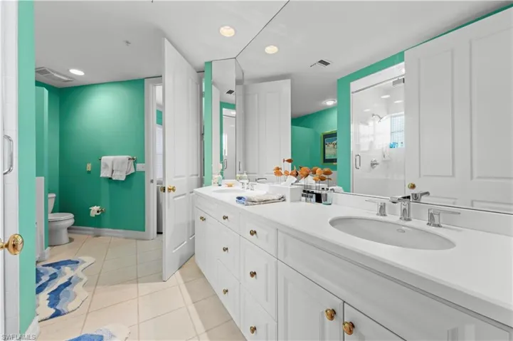 Full bath featuring double vanity, a shower stall, toilet, tile patterned flooring, and recessed lighting