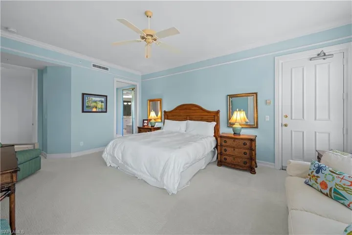 Carpeted bedroom with baseboards, crown molding, a ceiling fan, and ensuite bathroom