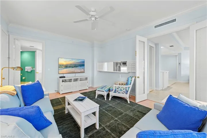 Living room featuring ornamental molding, a ceiling fan, and baseboards