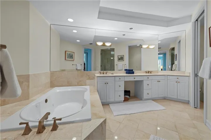 Bathroom with double vanity, a jetted tub, and recessed lighting