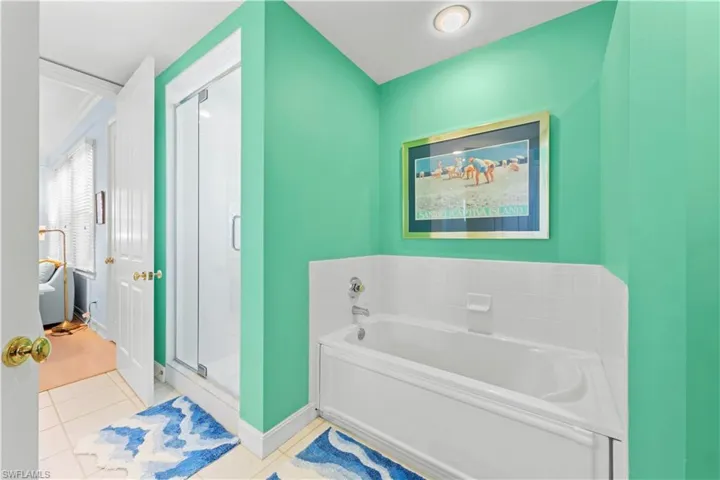 Bathroom featuring a garden tub, a stall shower, tile patterned flooring, and baseboards