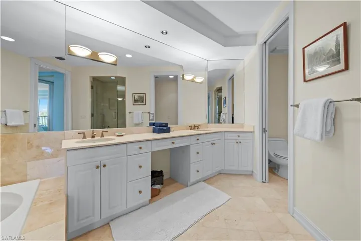 Bathroom with double vanity, toilet, a bath, an enclosed shower, and recessed lighting