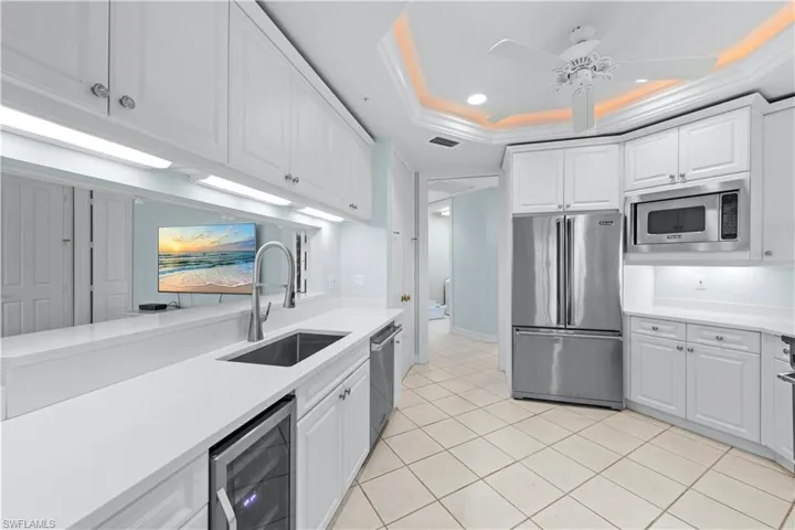 Kitchen with appliances with stainless steel finishes, wine cooler, a sink, light countertops, and recessed lighting