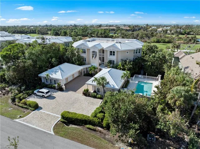 View from above of property with a pool and a tree filled landscape