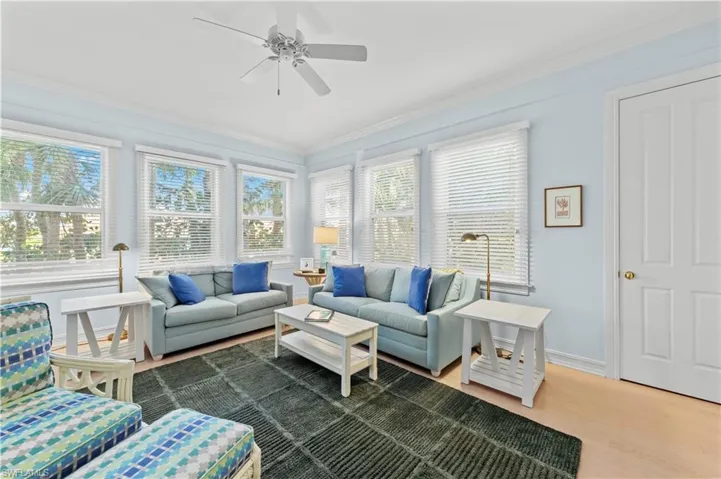 Living room with ceiling fan, ornamental molding, wood finished floors, healthy amount of natural light, and baseboards