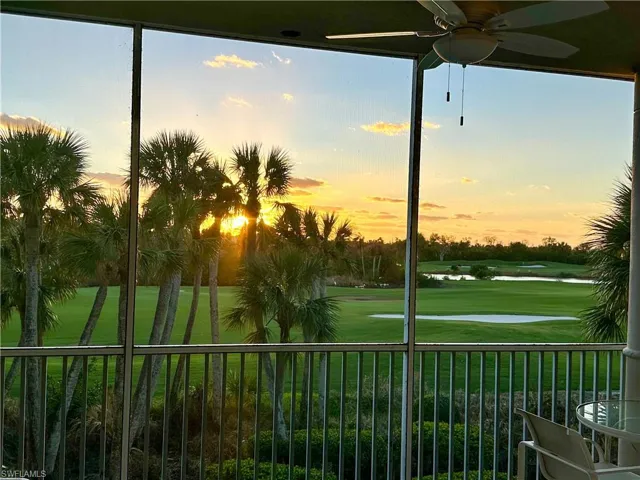 Yard at dusk with view of golf course, a ceiling fan, and a balcony