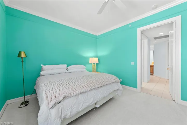 Carpeted bedroom with baseboards, ornamental molding, and a ceiling fan