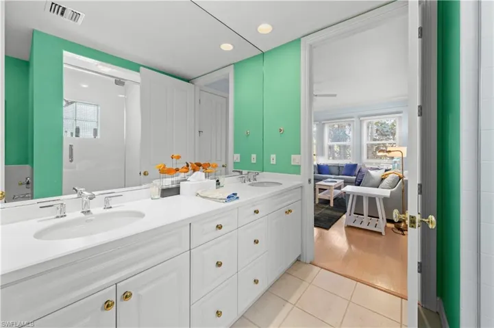Full bath with double vanity, tile patterned flooring, recessed lighting, an enclosed shower, and ensuite bath