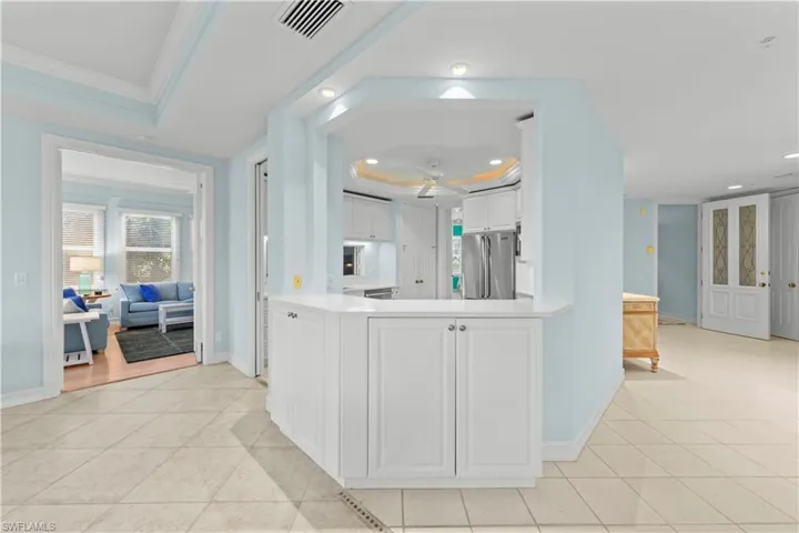 Kitchen with a tray ceiling, freestanding refrigerator, recessed lighting, ceiling fan, and crown molding