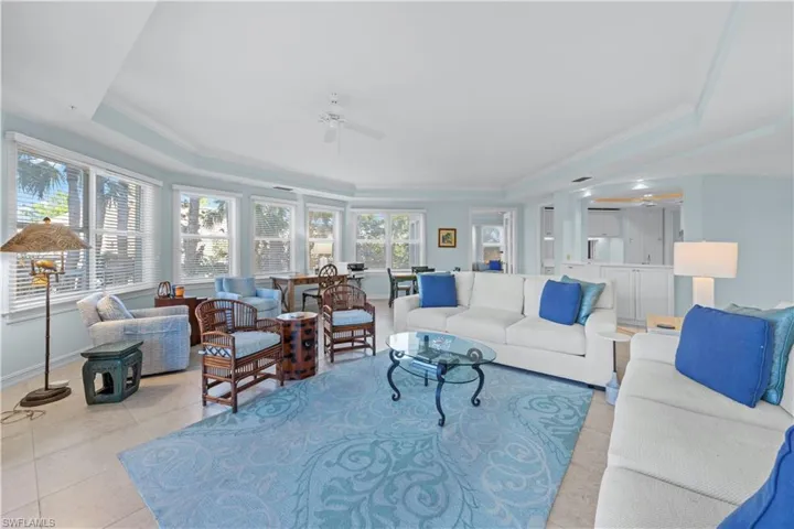 Living area with a tray ceiling, a ceiling fan, baseboards, ornamental molding, and light tile patterned floors