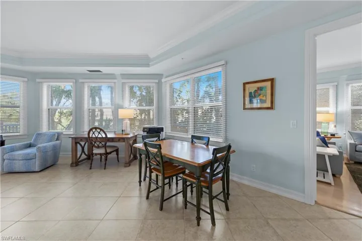 Dining room featuring ornamental molding, a tray ceiling, baseboards, and light tile patterned flooring