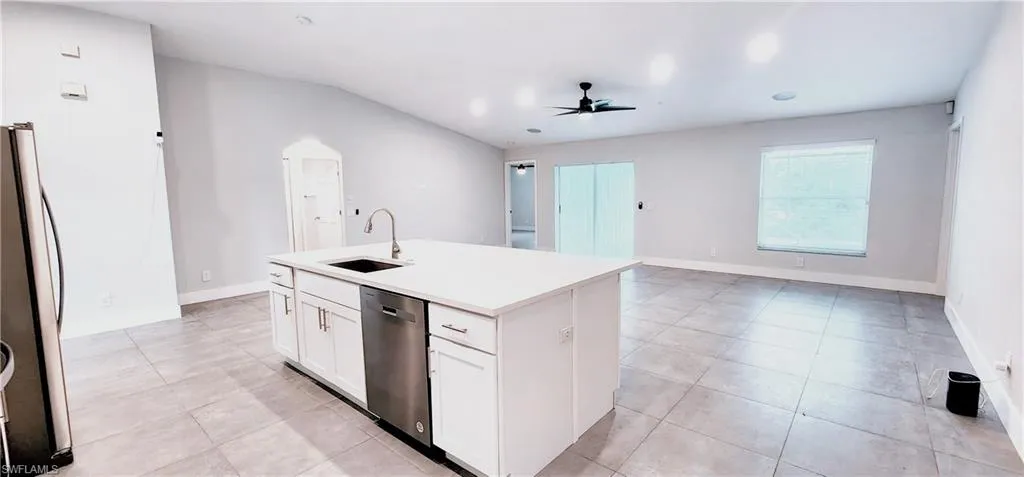 Kitchen featuring an island with sink, stainless steel appliances, sink, white cabinets, and ceiling fan