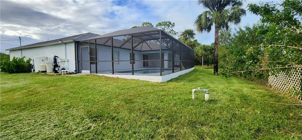 Rear view of property with a lanai and a yard