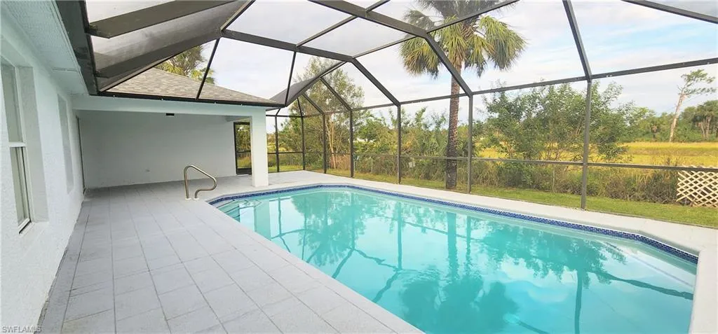 View of swimming pool with a patio and glass enclosure