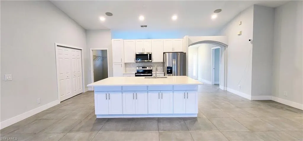 Kitchen featuring white cabinets, stainless steel appliances, sink, and a kitchen island with sink