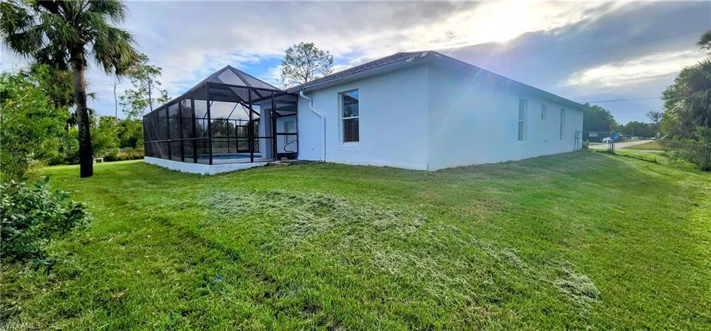 Rear view of property featuring a lanai and a lawn