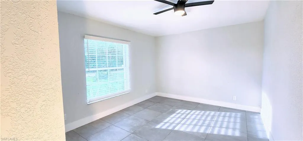 Unfurnished room featuring dark tile patterned flooring and ceiling fan