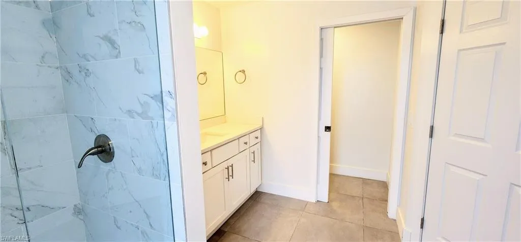 Bathroom with vanity, a tile shower, and tile patterned floors