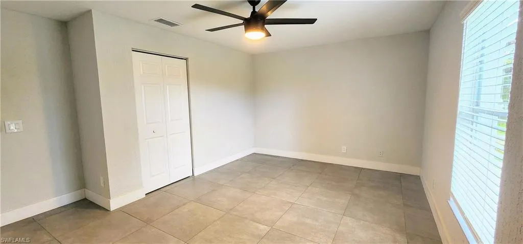 Unfurnished bedroom featuring a closet, light tile patterned floors, and ceiling fan