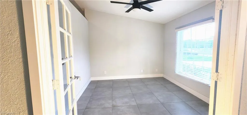 Tiled spare room featuring ceiling fan