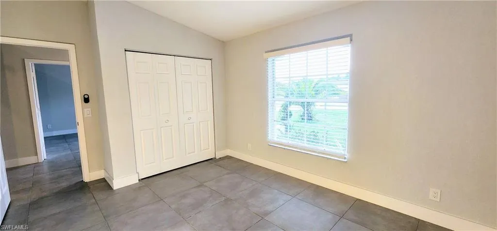Unfurnished bedroom with multiple windows, a closet, tile patterned flooring, and vaulted ceiling