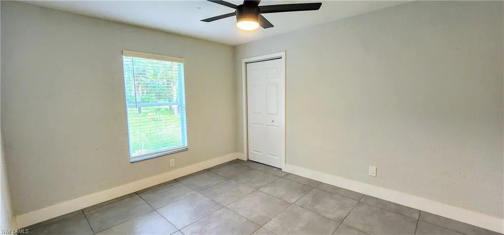 Unfurnished room with light tile patterned floors and ceiling fan