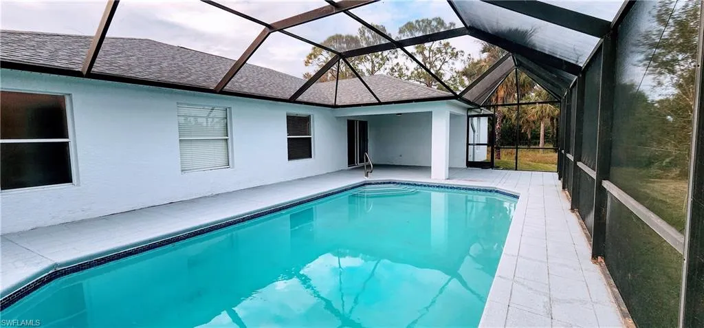 View of pool featuring a patio area and glass enclosure