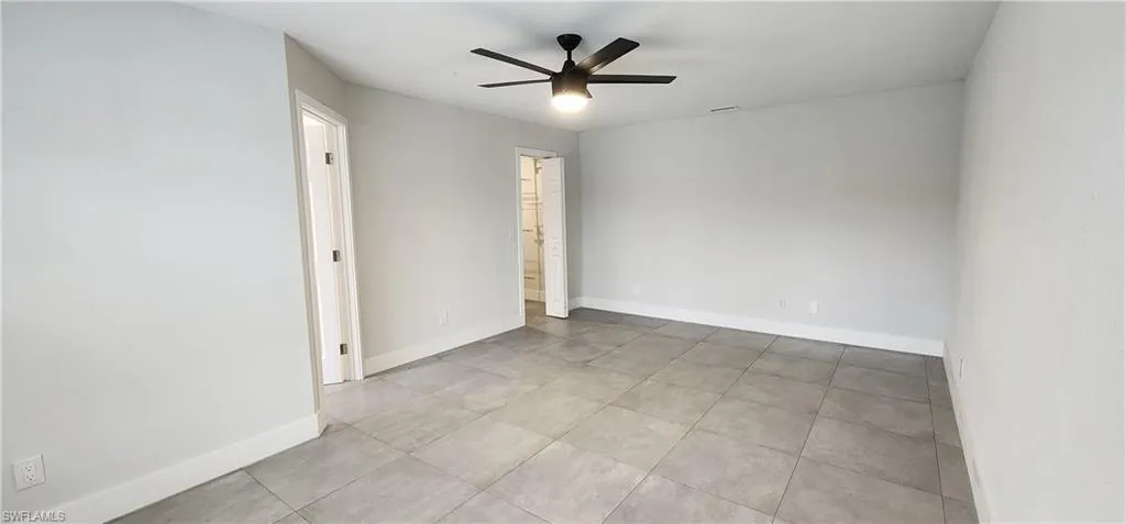 Tiled spare room featuring ceiling fan