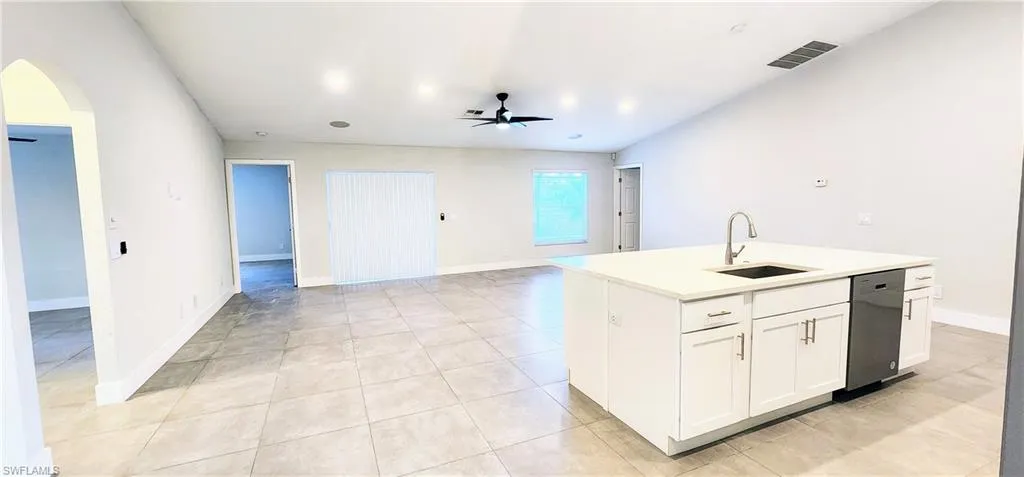 Kitchen featuring white cabinetry, dishwasher, sink, and a kitchen island with sink