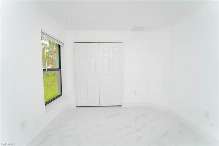Unfurnished bedroom with light marble finish flooring and a closet