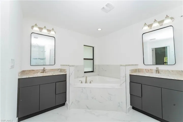 Full bath with a bath, two vanities, recessed lighting, light marble finish floors, and a marble finish shower